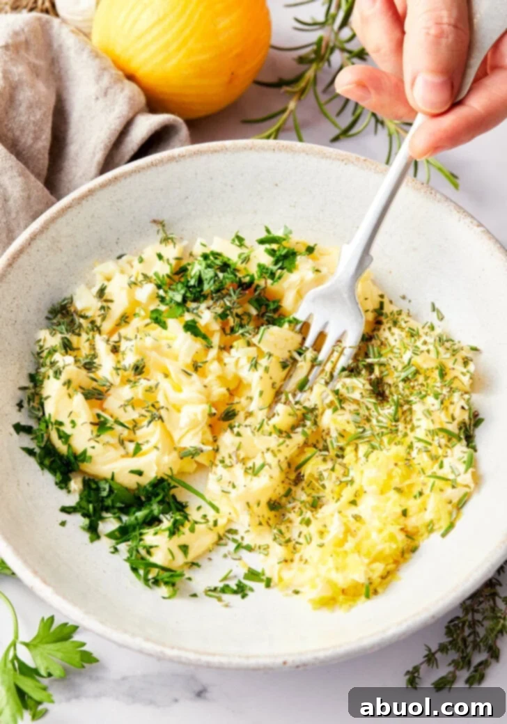 Fresh herbs being pressed into softened butter, creating an aromatic rub for game hens.