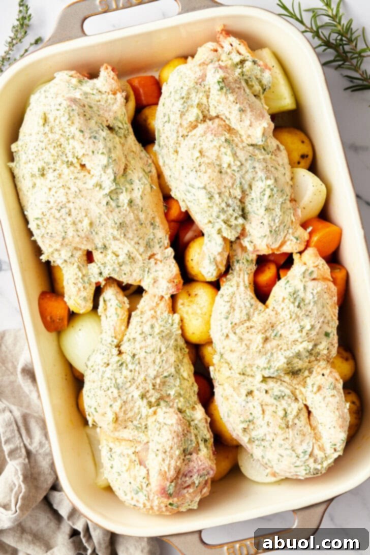 Unbaked Cornish hens arranged in a baking dish on a bed of raw vegetables, ready for the oven.