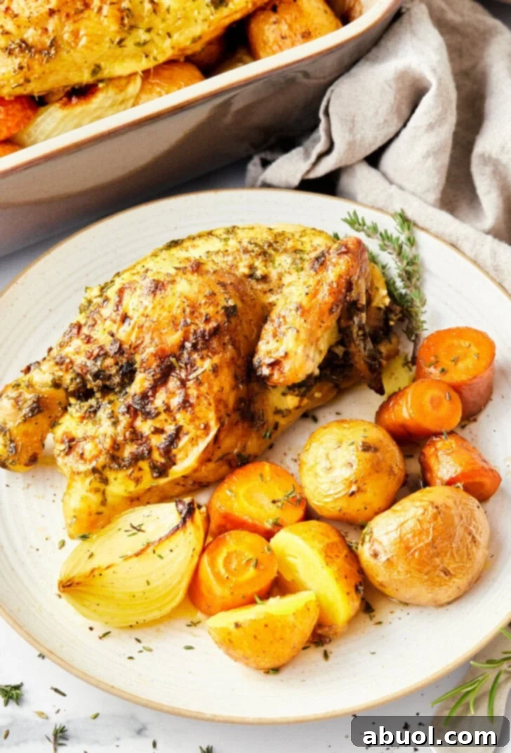 A perfectly roasted Cornish game hen half served on a plate with an assortment of colorful roasted vegetables.