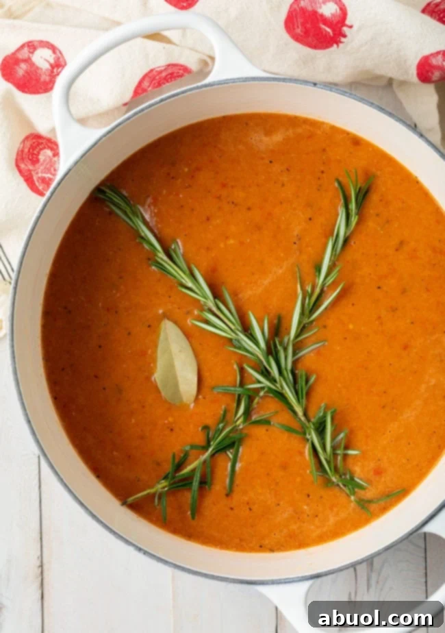 Roasted Tomato and Basil Velvet 2 Overhead shot of roasted tomato soup in a large Dutch oven with sprigs of rosemary on top.