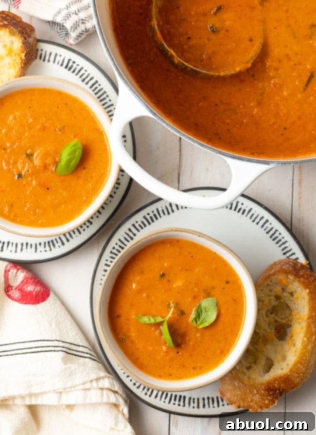 Roasted Tomato and Basil Velvet 3 Two bowls of tomato soup with a large pot of soup next to them.