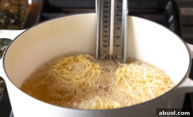 Preparing crispy fried noodles, an essential garnish for authentic Khao Soi.