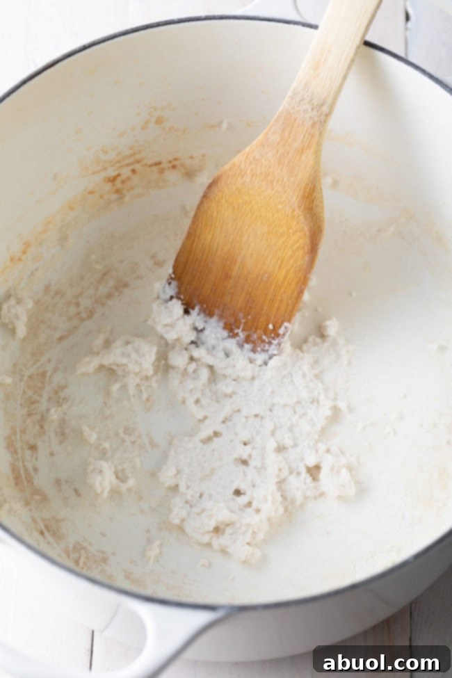 The essential step of reducing coconut milk to form a thick, flavorful base for the Khao Soi curry.