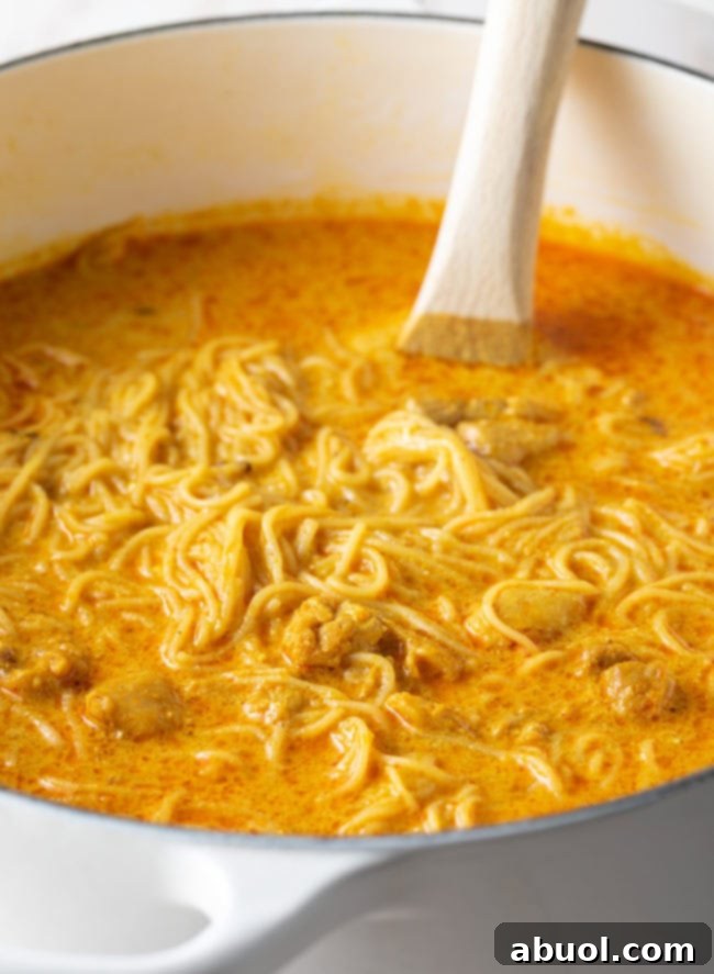 The creamy and rich texture of the Khao Soi soup base simmering gently.