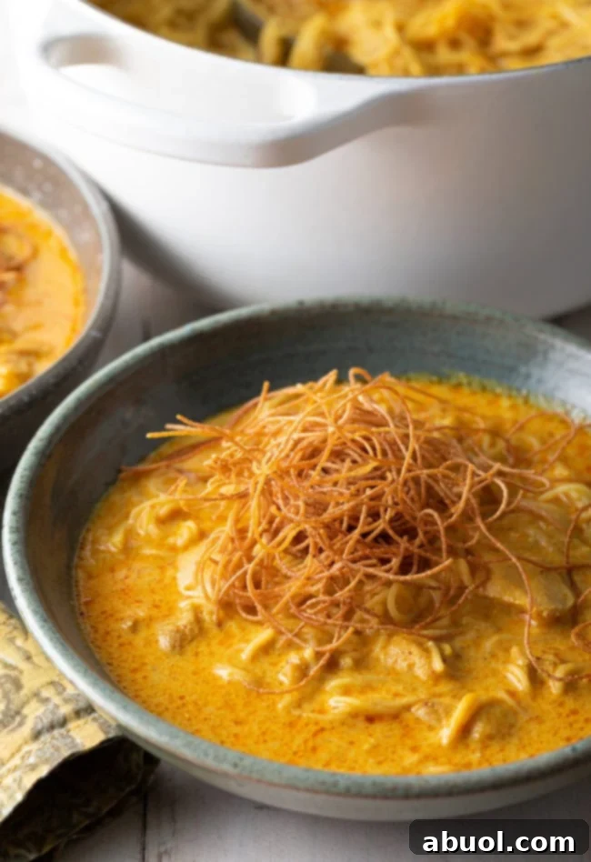 A close-up of crispy fried noodles meticulously placed on top of a finished bowl of Khao Soi.