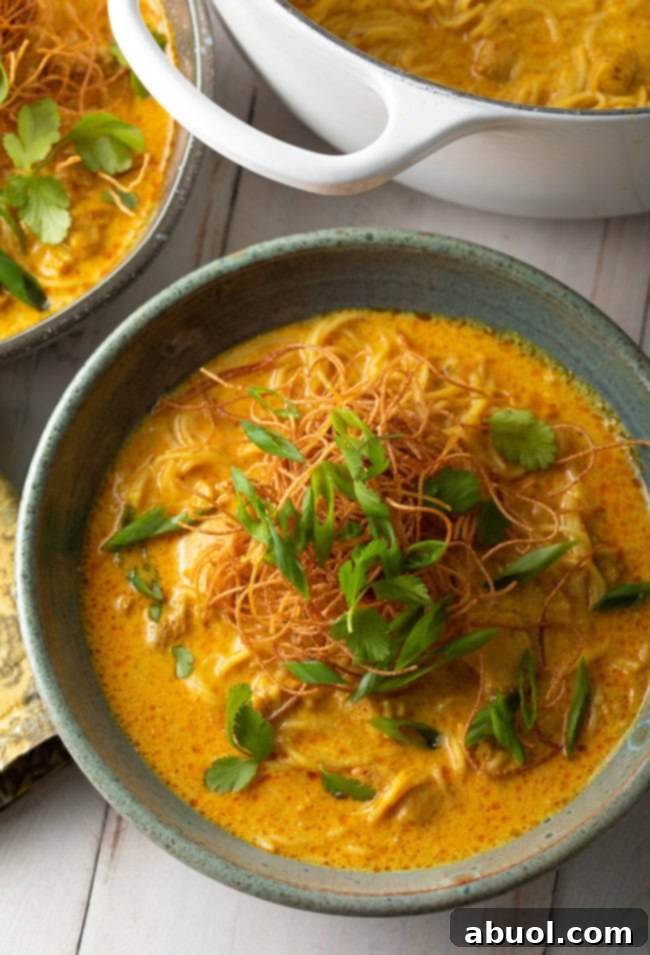 A beautifully garnished bowl of Khao Soi, adorned with fresh herbs and a lime wedge.