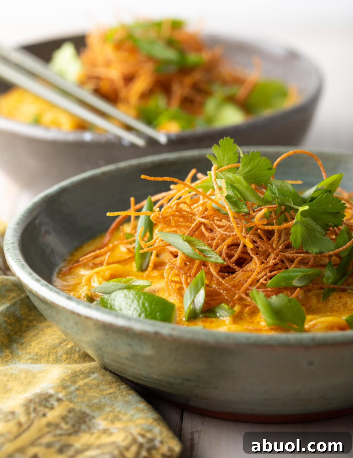 A side view of two elegant gray bowls of Thai Khao Soi Coconut Curry Soup, inviting you to share this delicious meal.