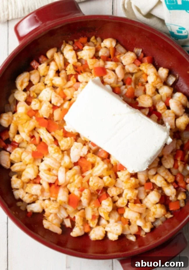 Close-up of raw shrimp being chopped into small pieces on a cutting board, a key step for the dip.
