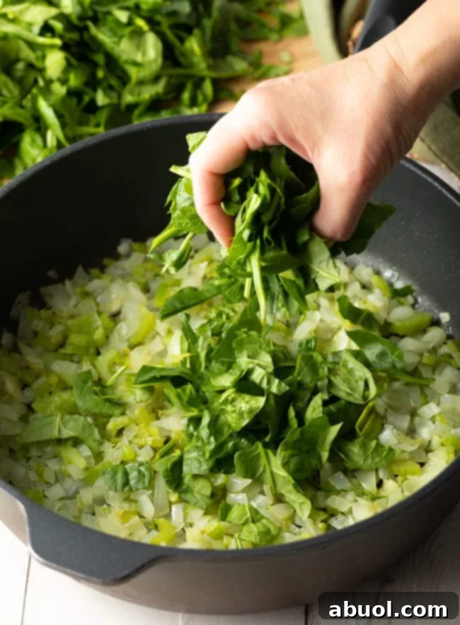 large pot full of the onion, celery and chopped spinach.