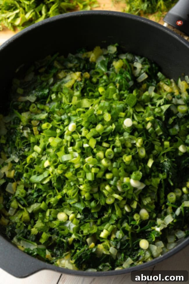 large pot of greens with added scallions to continue cooking.