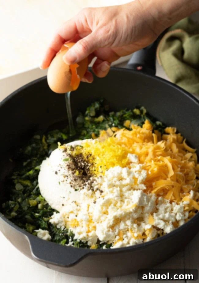 Top view of the pot of greens with the dairy ingredients and the  eggs added into the mix.
