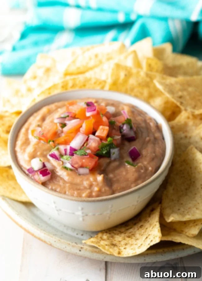 Bean dip served in a white bowl next to chips. 
