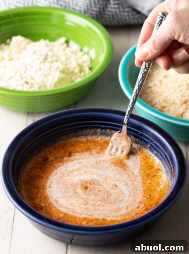 Hand whisking together buttermilk and cajun seasoning. 