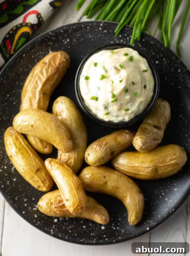 easy aioli sauce in a black bowl on a black plate with fingerling potatoes.
