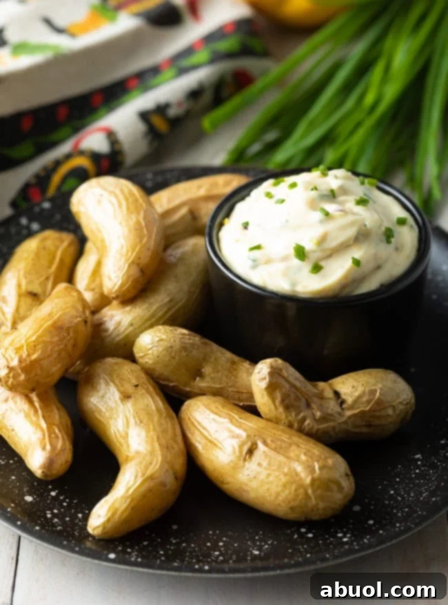 A bowl of garlic aioli on a plate with fingerling potatoes.
