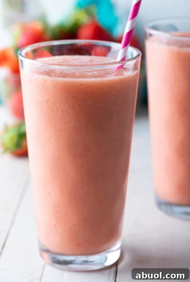 A tall glass filled with the vibrant Caribbean Way smoothie, featuring a pink striped straw.