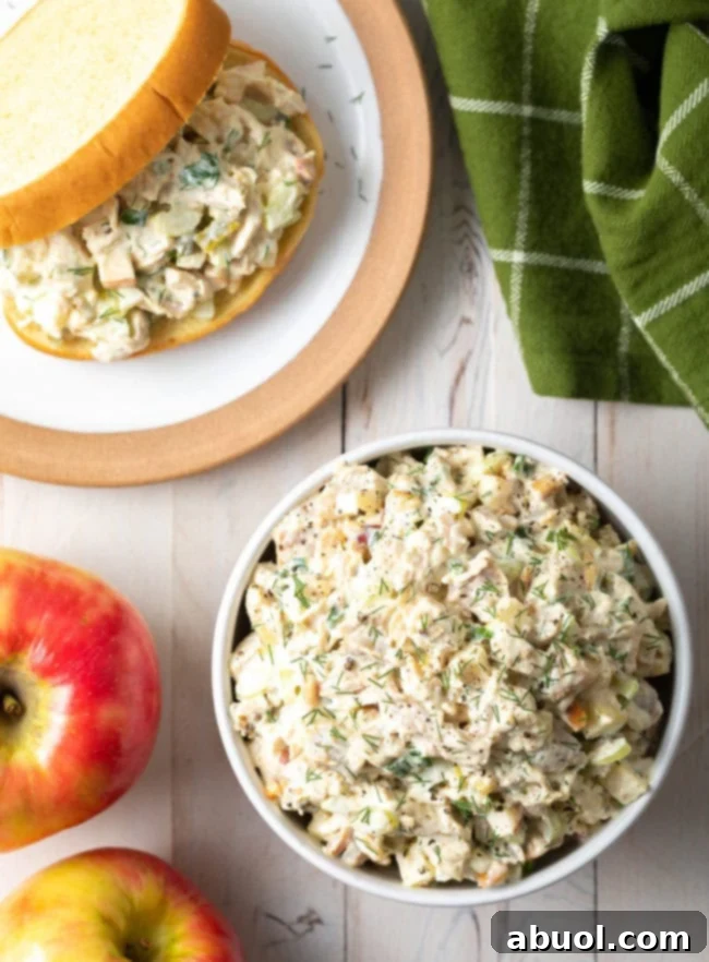 Top down view of southern chicken salad in a white bowl next to a plate with a chicken salad sandwich.