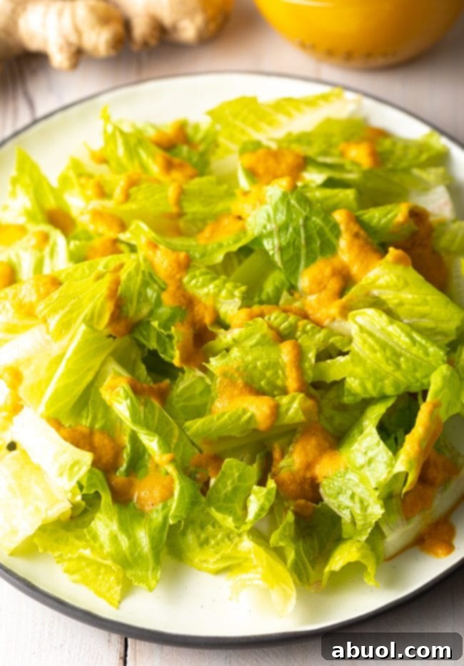 Japanese Ginger Salad Dressing drizzled generously over a bed of fresh lettuce leaves on a white plate, ready to be served as a healthy side.