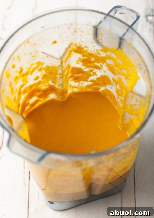 Blender jar containing the mixed and pureed ingredients for Japanese ginger dressing, showcasing a perfectly smooth, vibrant orange, and creamy texture after blending.