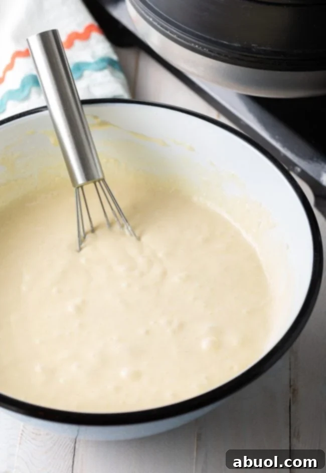 Freshly mixed waffle batter, with a perfectly smooth consistency, resting in a large mixing bowl.