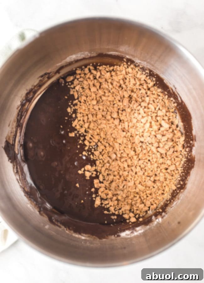 Adding crunchy toffee bits into the chocolate cookie dough, ready for mixing.