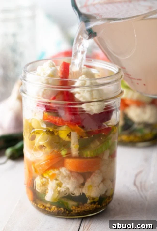 Zesty Italian Giardiniera 9 Hot pickling brine being poured into jars of vegetables.