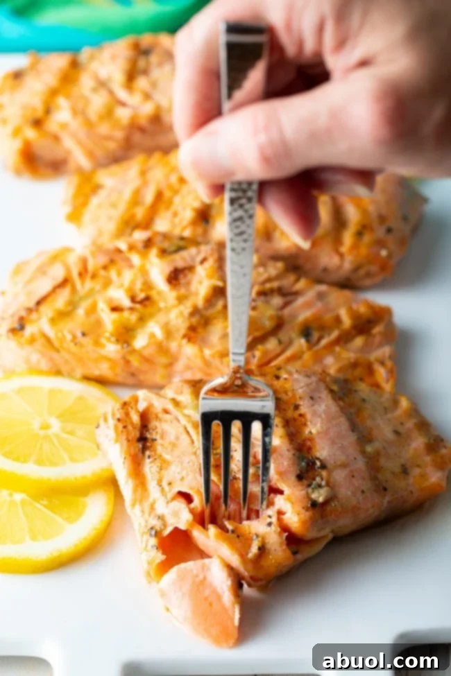 Hand removing a piece of salmon with fork. 