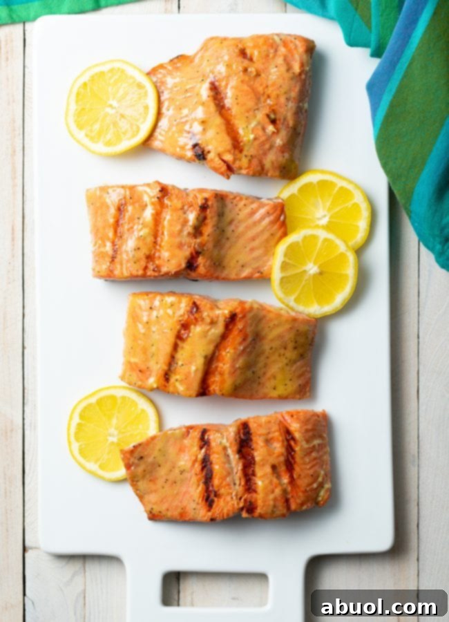Top down view of grilled salmon on a platter with slices of lemon. 