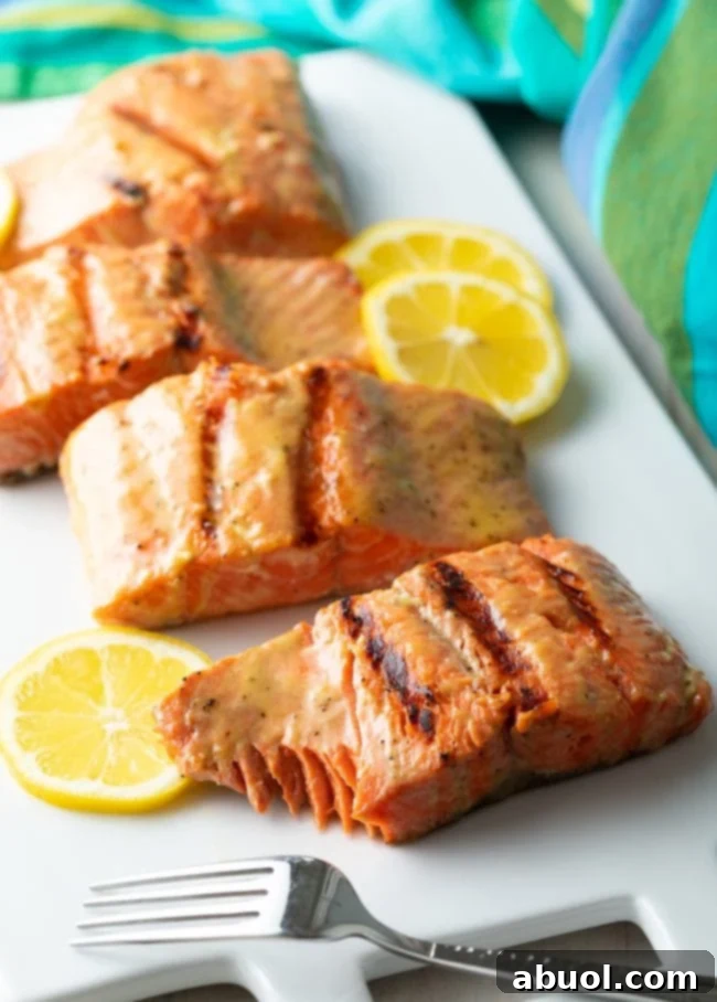 Cooked salmon fillets on a white platter with a fork and bite removed. 