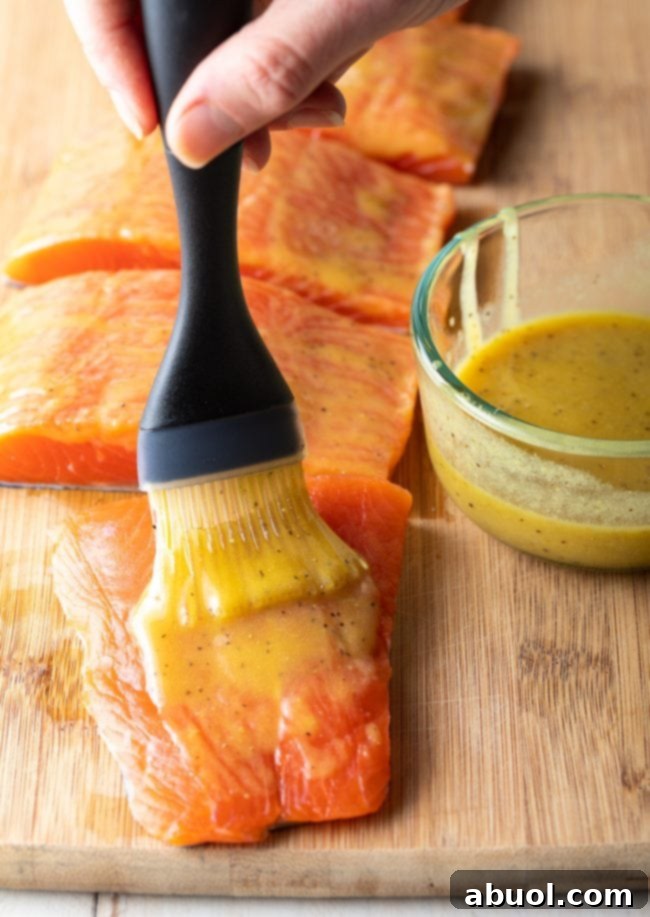 A hand is brushing the marinade over the salmon fillets. 