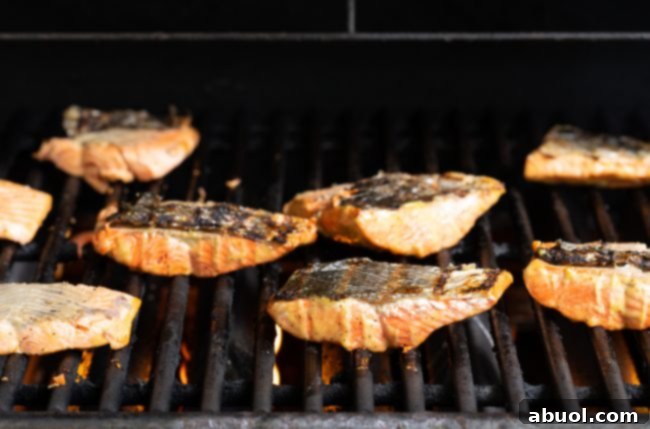 Salmon fillets being grilled skin-side up on a grill. 