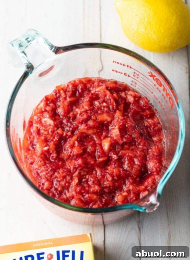 A top-down perspective of beautifully pureed strawberries in a clear glass liquid measuring cup, showing the ideal consistency for starting a batch of homemade jam.