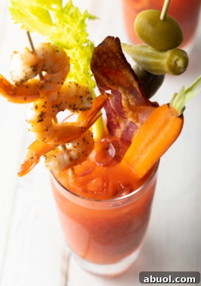 top view of bloody mary mix recipe with shrimp skewer, bacon and a carrot on top. 
