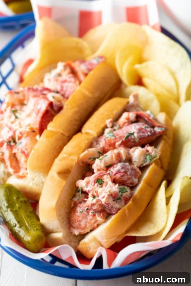 Two authentic Maine lobster rolls artfully arranged in a rustic basket, accompanied by crispy potato chips and a vibrant pickle spear.