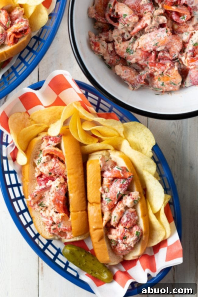 An overhead shot showcasing freshly assembled Maine lobster rolls, beautifully arranged in a serving basket alongside crispy potato chips, with additional lobster meat visible in the background.