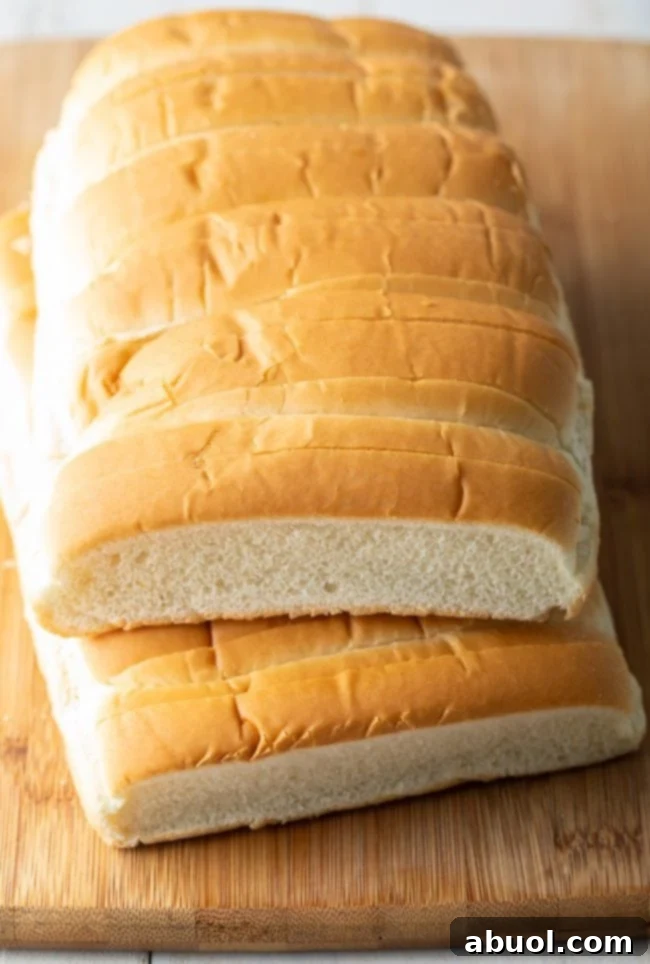 A stack of classic New England-style hot dog buns, distinguished by their split tops.
