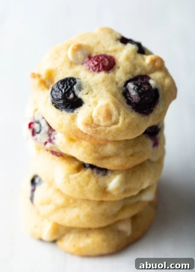 Cookies with blueberries and white chocolate chips stacked on top of each other.