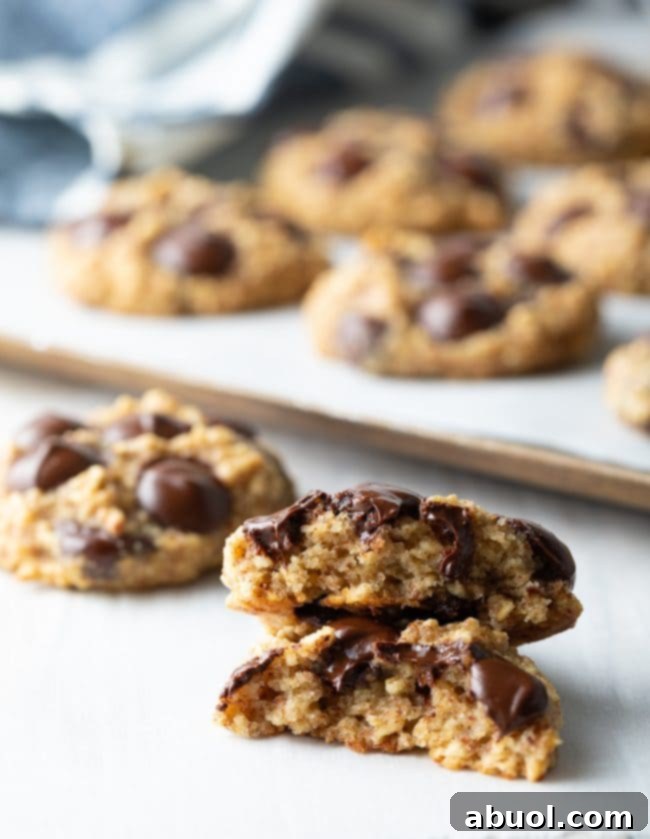 A banana oat cookie is broken in half, with both halves stacked on top of each other, displaying its soft, inviting interior.