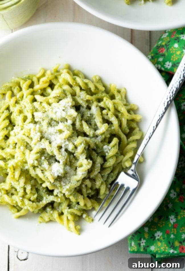 Overhead shot of pesto pasta in a white bowl with a fork. 
