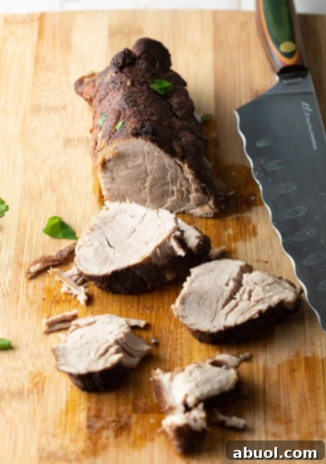 A skilled hand expertly slicing a perfectly cooked pork tenderloin on a cutting board with a sharp knife, revealing its tender, juicy interior.
