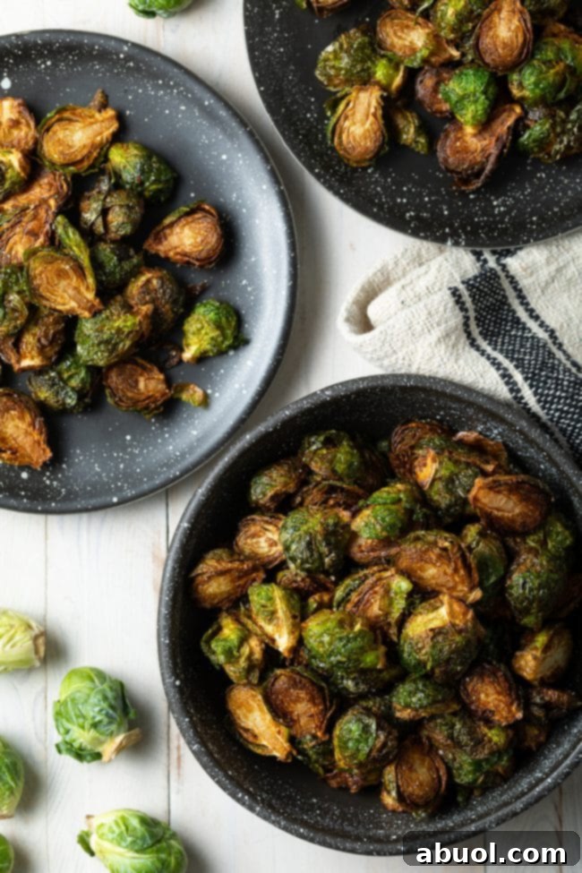 Crispy Fried Brussels Sprouts in a black bowl and plate, garnished with balsamic glaze.