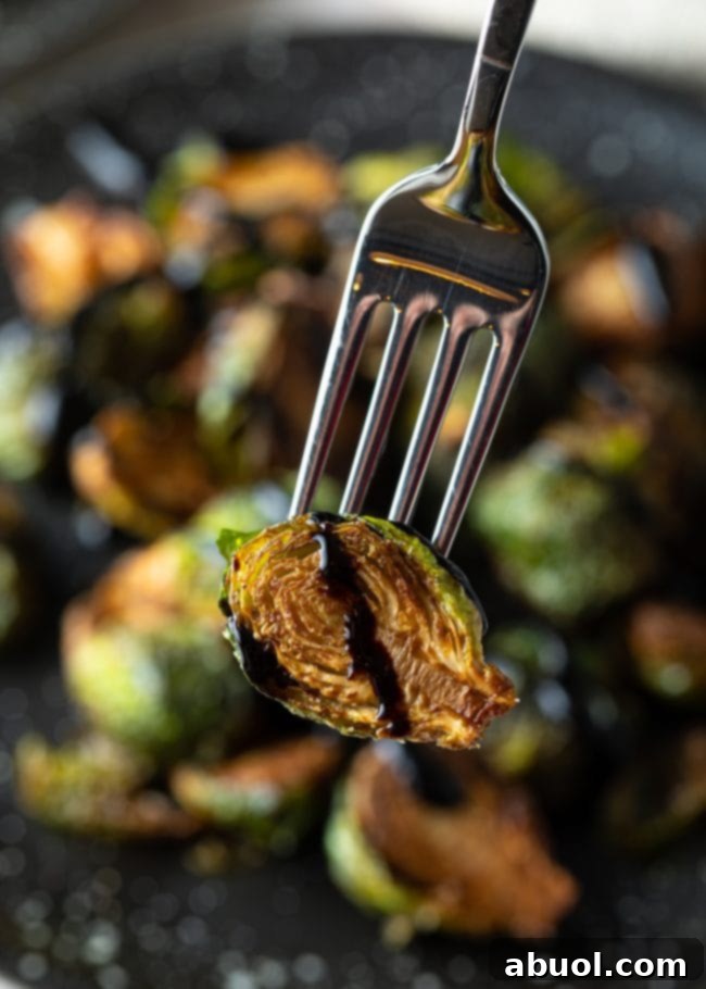 A crispy Brussels sprout with balsamic glaze being picked up with a fork, ready to eat.