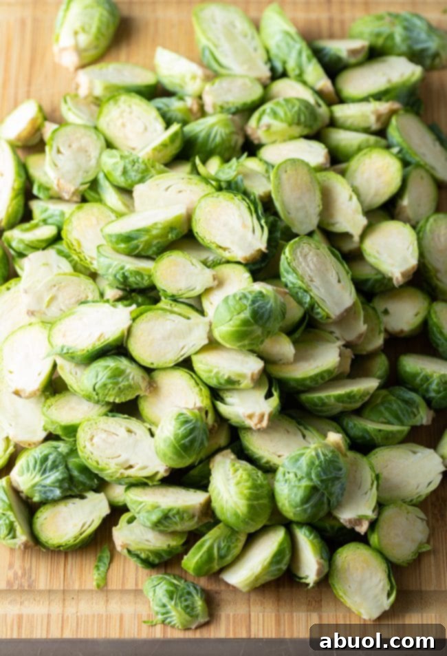 Fresh Brussels sprouts, trimmed and cut in half, laid out on a bamboo cutting board.