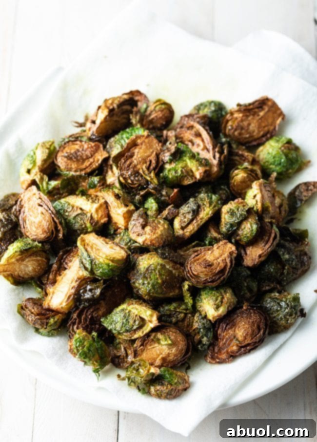 Freshly fried Brussels sprouts being strained on paper towels on a plate, absorbing excess oil.
