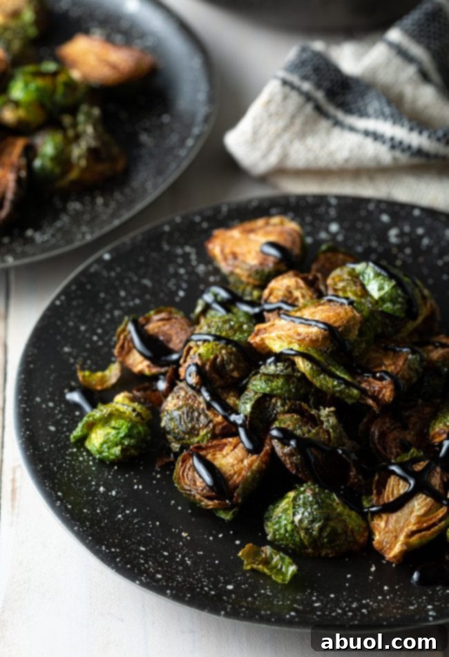 A plate of fried Brussels sprouts, perfectly golden, topped with a rich balsamic glaze.
