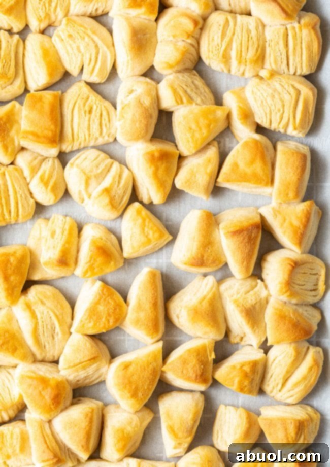Golden biscuit triangles arranged on a baking sheet lined with parchment paper, fresh out of the oven.