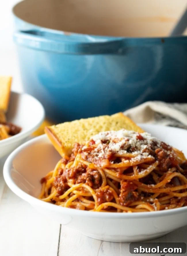 A bowl of rich spaghetti sauce recipe with meat, served alongside golden garlic bread