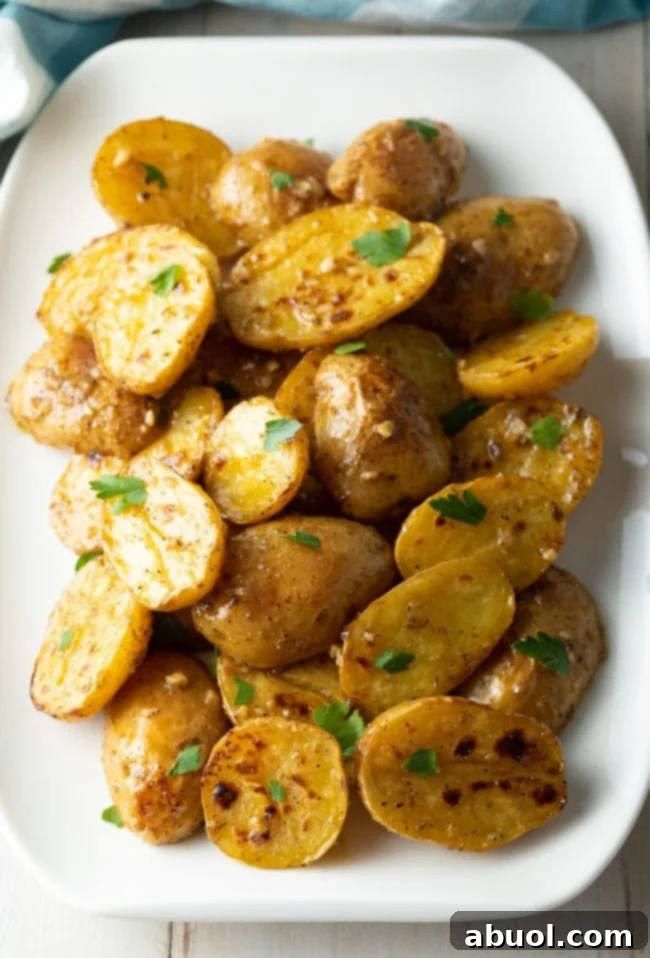 Baby greek potatoes with lemon, garlic, and parsley resting on a white platter, ready to be served.