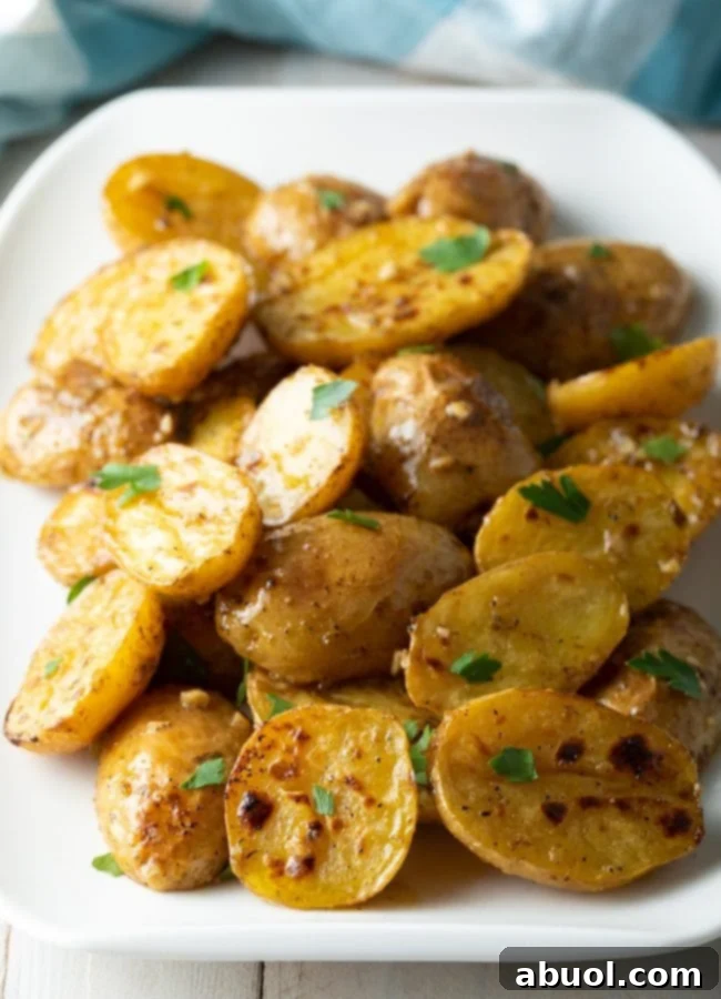 Lemon garlic roasted greek potatoes close up with parsley garnish on a white plate, highlighting the golden crispiness and vibrant colors.