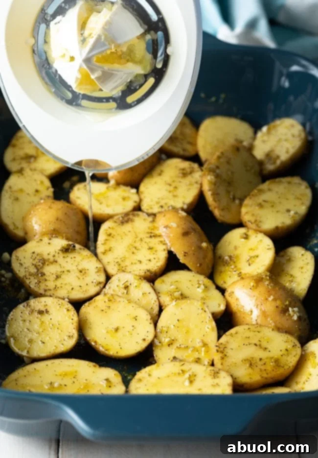 Lemon and seasonings drizzled over potatoes in casserole dish before roasting.